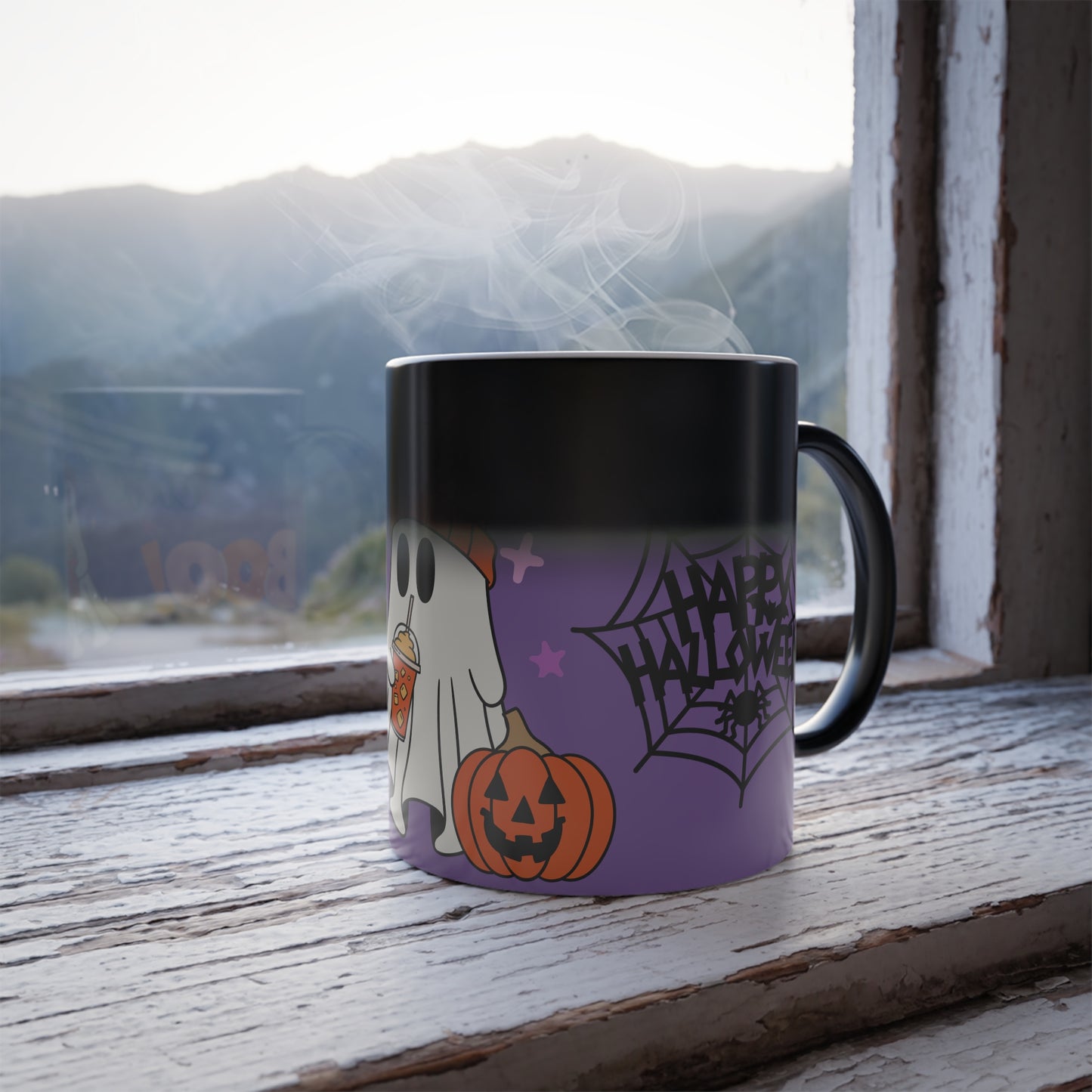Mid-activation view of the Wicked Cute Halloween Boo Magic Morphing Mug, showing the design partially revealed. As the mug heats up, the dark layer fades, gradually exposing the vibrant ghost, pumpkin, and 'Happy Halloween' design against the purple background.