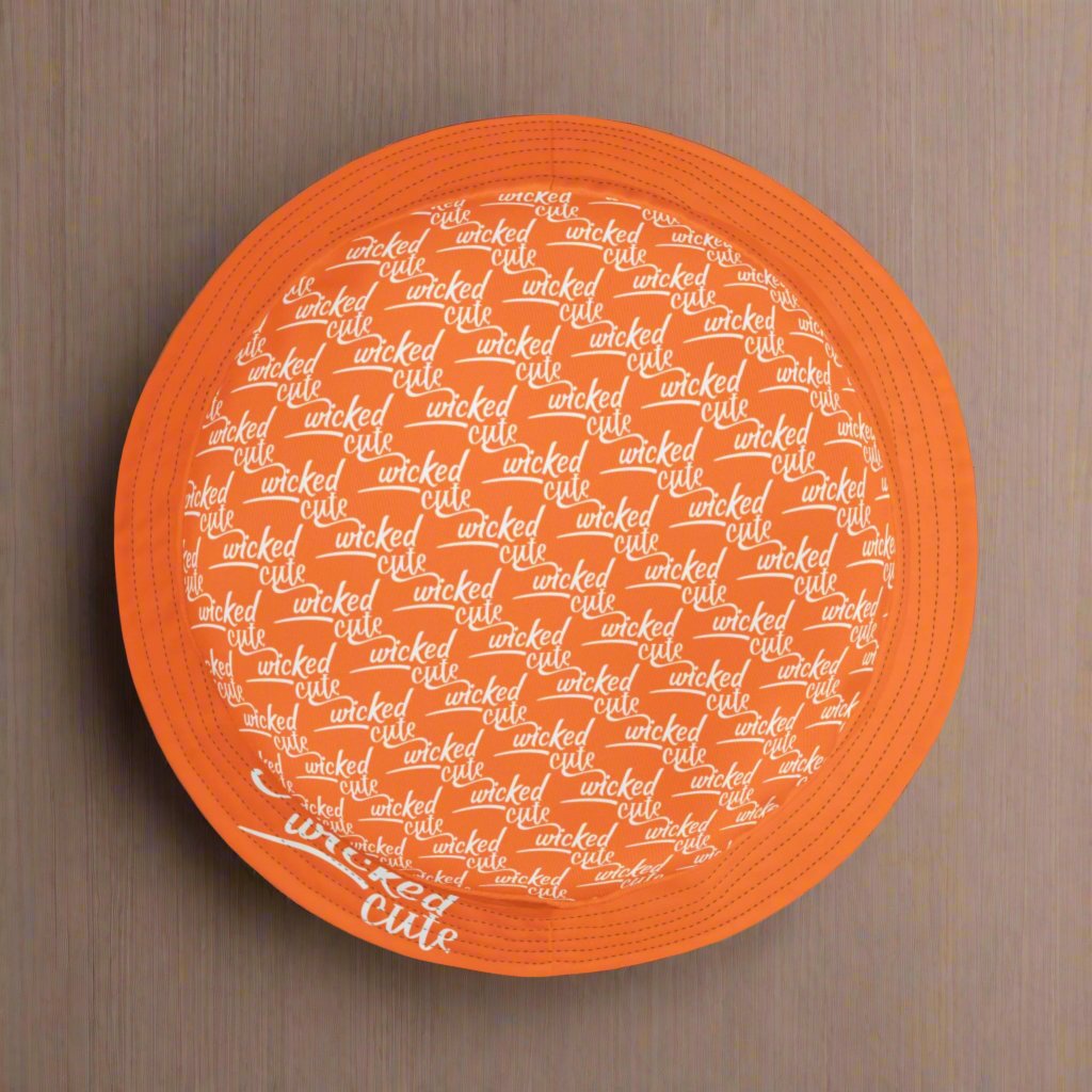 Top view of the Wicked Cute Black Cat Halloween Bucket Hat highlighting the repeating pattern of "Wicked Cute" white text on orange fabric.