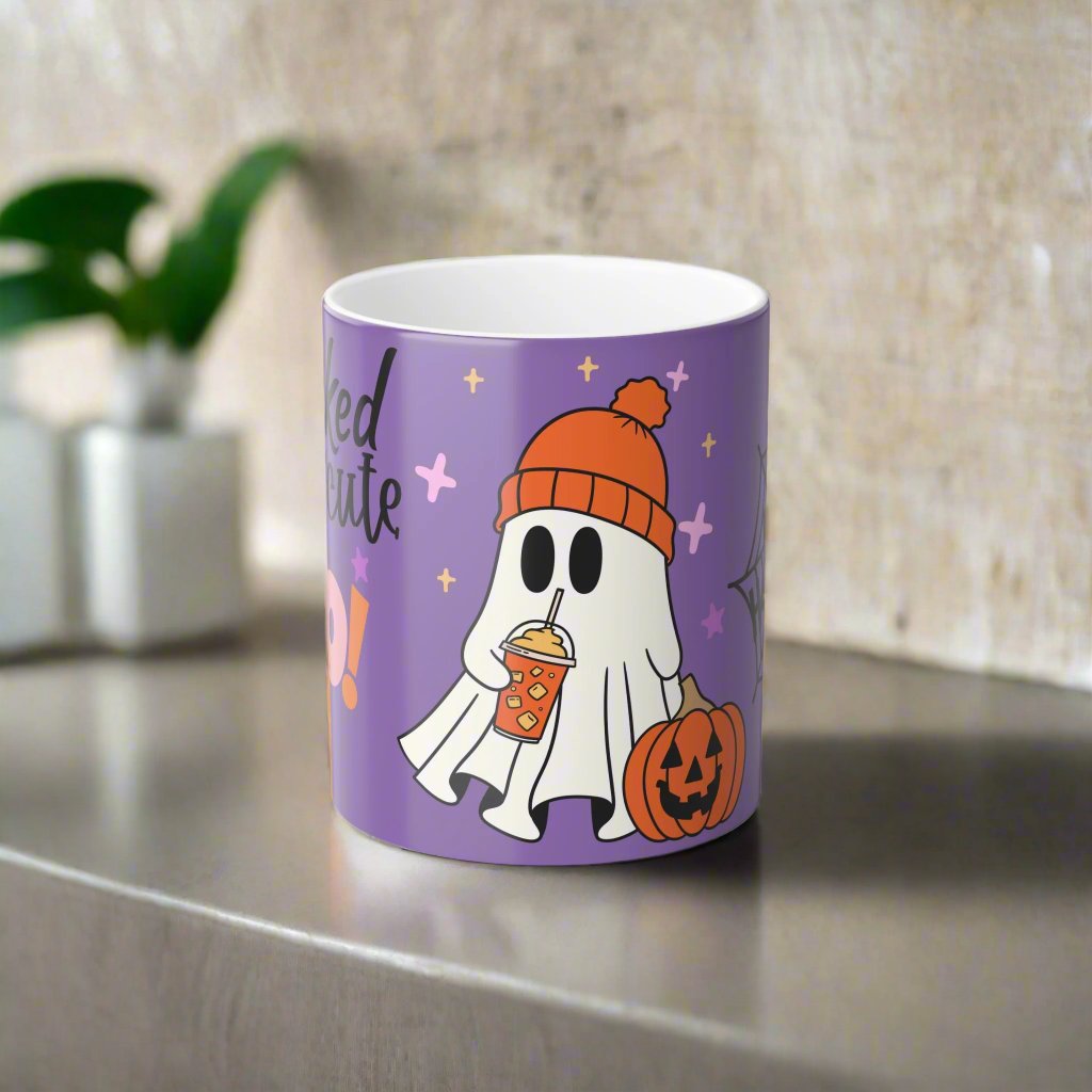 Front view of Wicked Cute Halloween Boo Magic Morphing Mug with a purple background, featuring a cute ghost in an orange beanie holding a pumpkin-themed drink, and a pumpkin on the side.