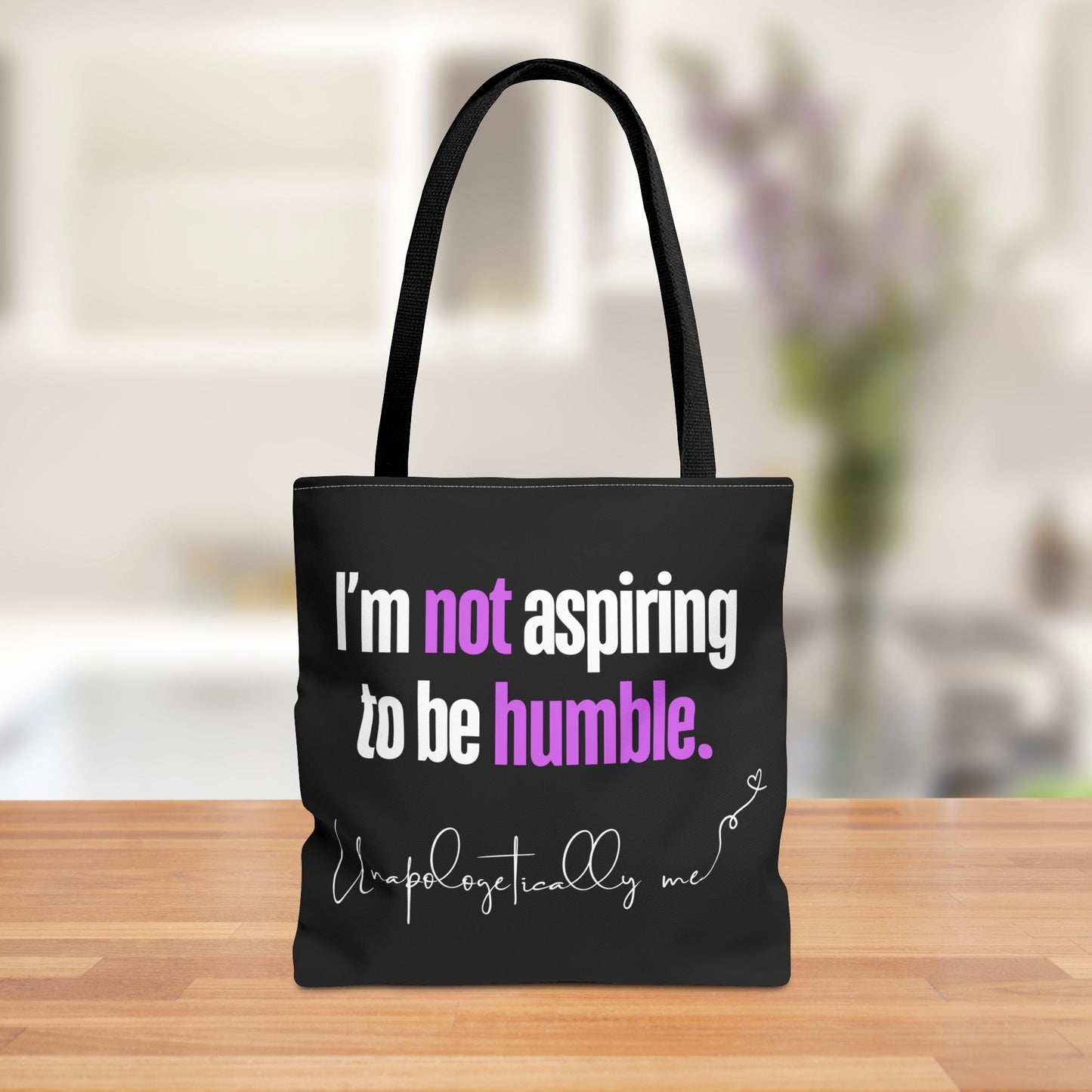 Front view of the black tote bag with the phrase “I’m not aspiring to be humble” printed in bold letters.