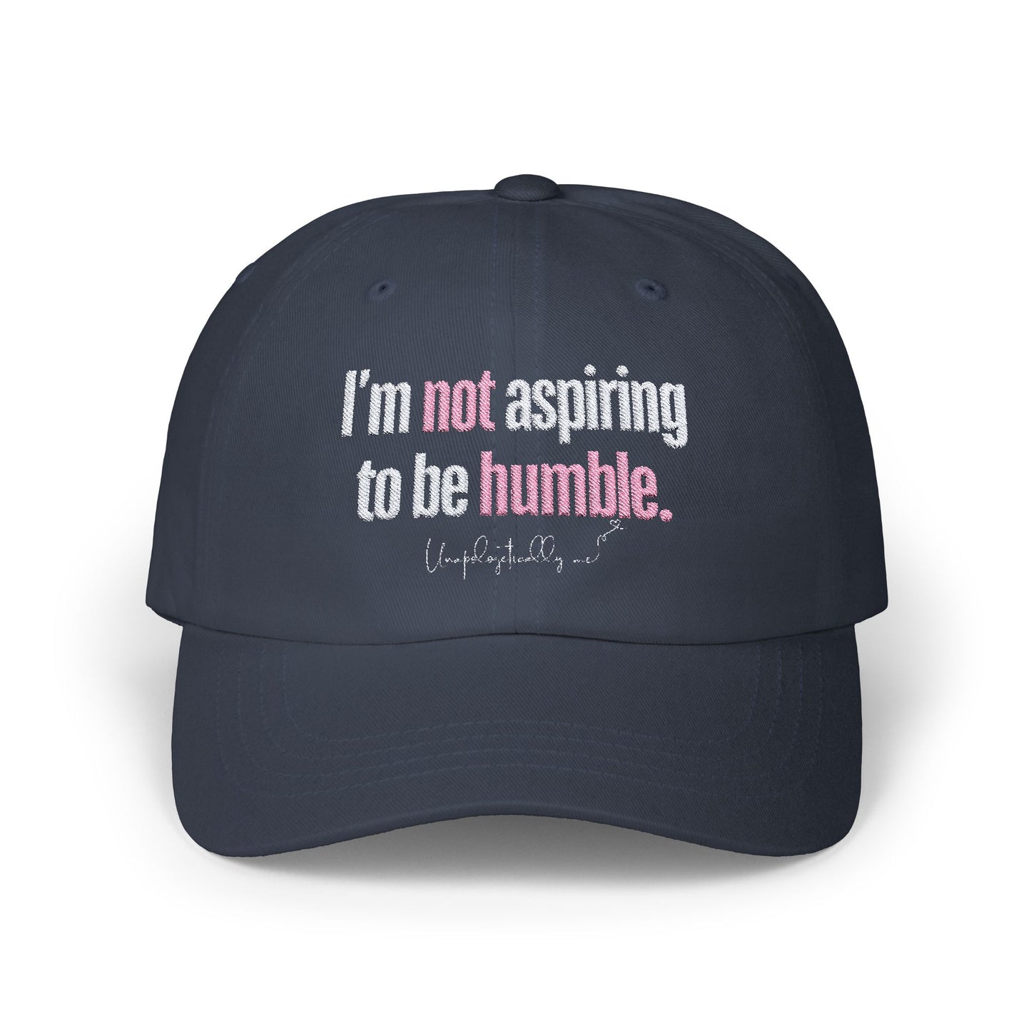 Front view of the navy blue dad hat with the phrase “I’m not aspiring to be humble” embroidered in bold.