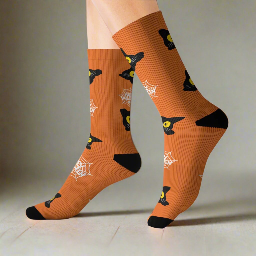 Orange Halloween socks featuring a playful black cat design with spider webs, worn on feet, showcasing a festive and spooky style.
