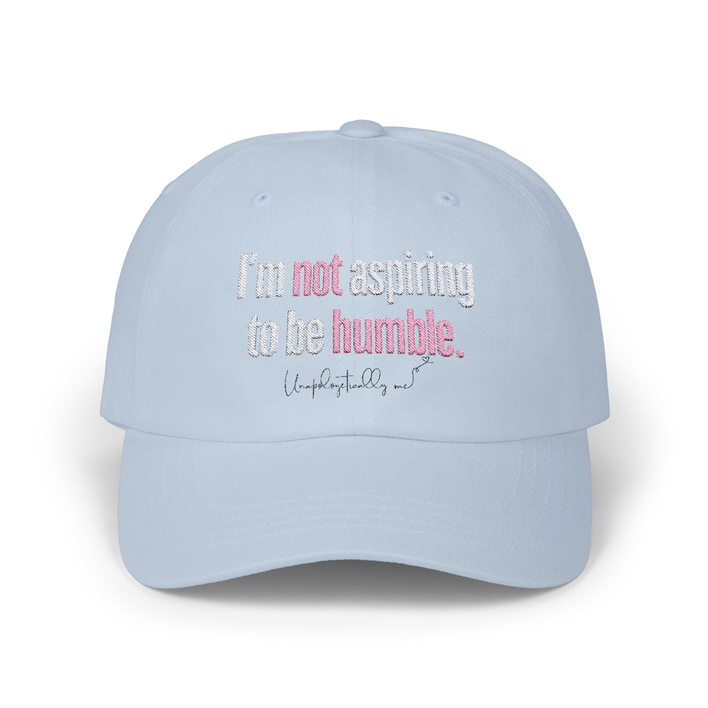 Front view of the light blue dad hat with the phrase “I’m not aspiring to be humble” embroidered in bold.