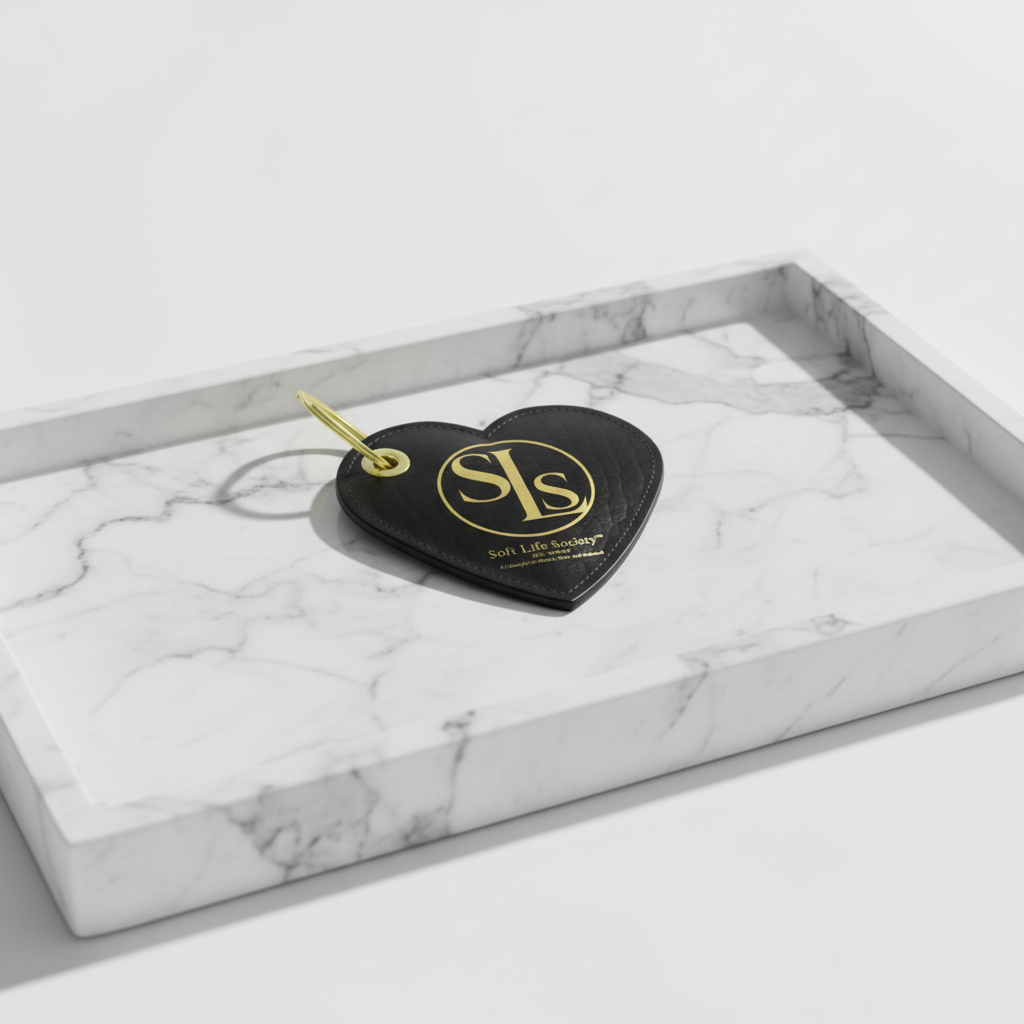 Heart-shaped keychain with 'SLS' logo on a marble tray