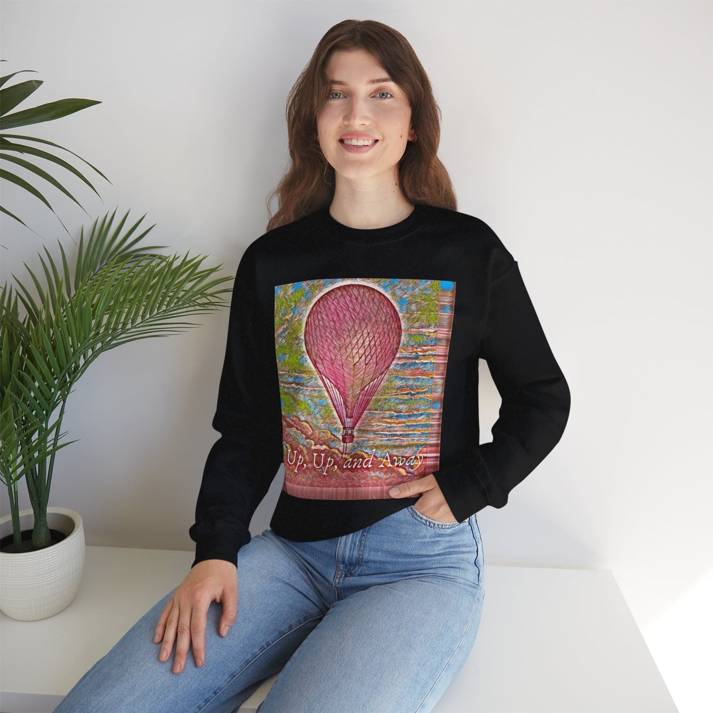 Lifestyle image of a woman wearing the pink hot air balloon sweatshirt in black, sitting indoors