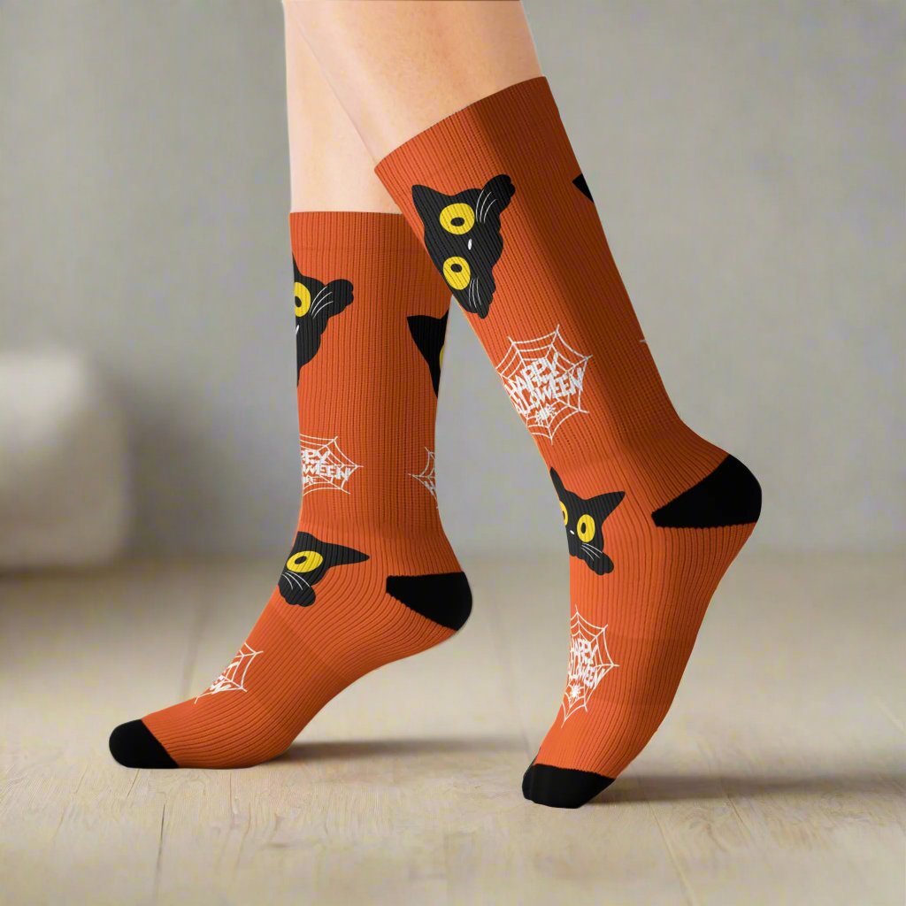 Orange Halloween socks featuring a playful black cat design with spider webs, worn on feet, showcasing a festive and spooky style.