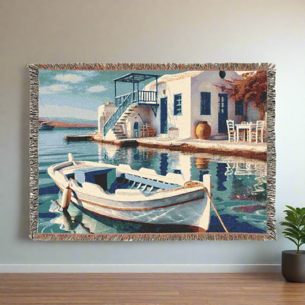 Woven blanket hung in a cozy, minimalistic room showing a serene Mediterranean coastal view, with a focus on the calm sea, white architecture, and a docked boat in a traditional setting.