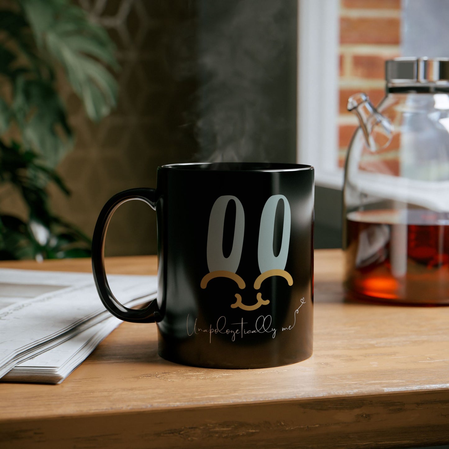 Lifestyle image of black "Unapologetically Me" mug on a desk, with motivational message displayed. 11oz