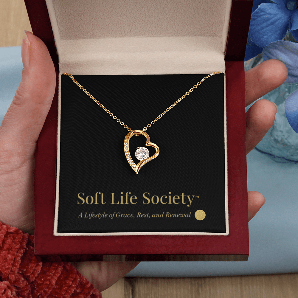 Close-up of gold Forever Love Necklace held in hand with Soft Life Society™ card.