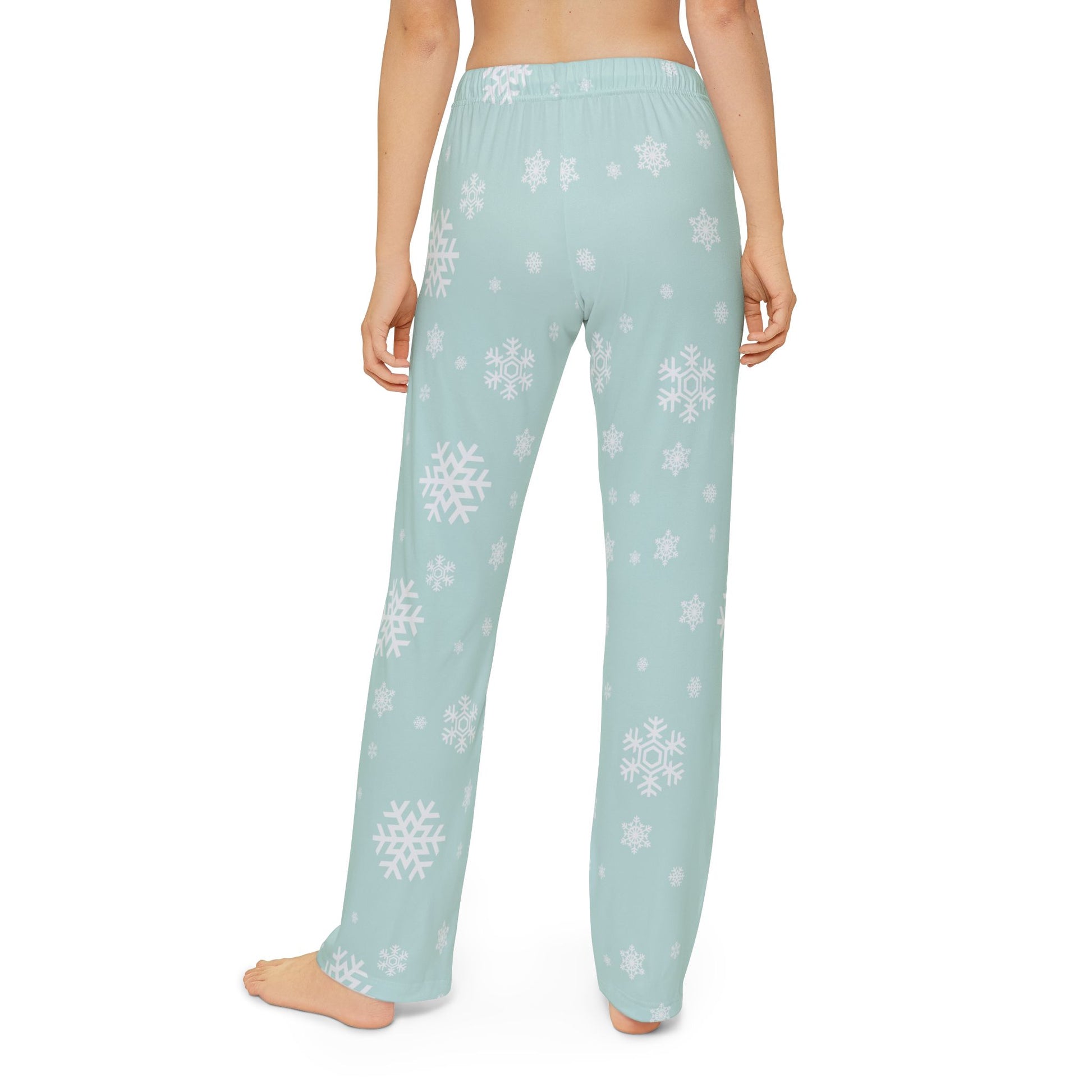 Back view of the child model in the snowflake pajama pants, highlighting the cozy fit and holiday-themed snowflake pattern against a mint background.