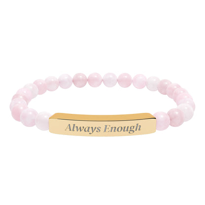 Rose quartz beaded stretch bracelet with engraved 18K gold bar reading “Always Enough”, shown on a white background.
