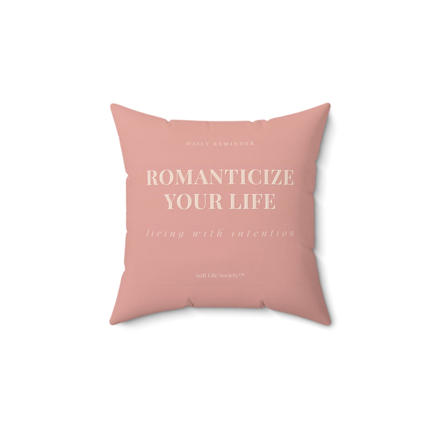 Pink pillow with text 'ROMANTICIZE YOUR LIFE' on a white background