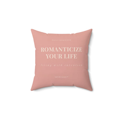 Pink pillow with text 'ROMANTICIZE YOUR LIFE' on a white background