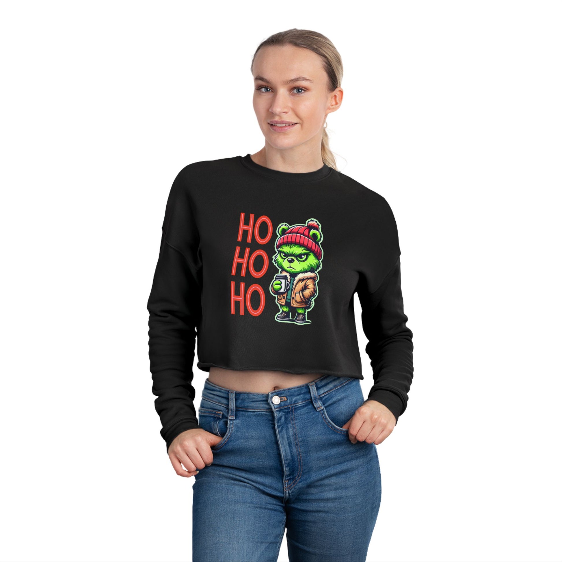 Lifestyle image of women wearing a black cropped sweatshirt featuring a festive teddy bear inspired by the Grinch, alongside 'HO HO OH' text for a cozy and playful holiday look.