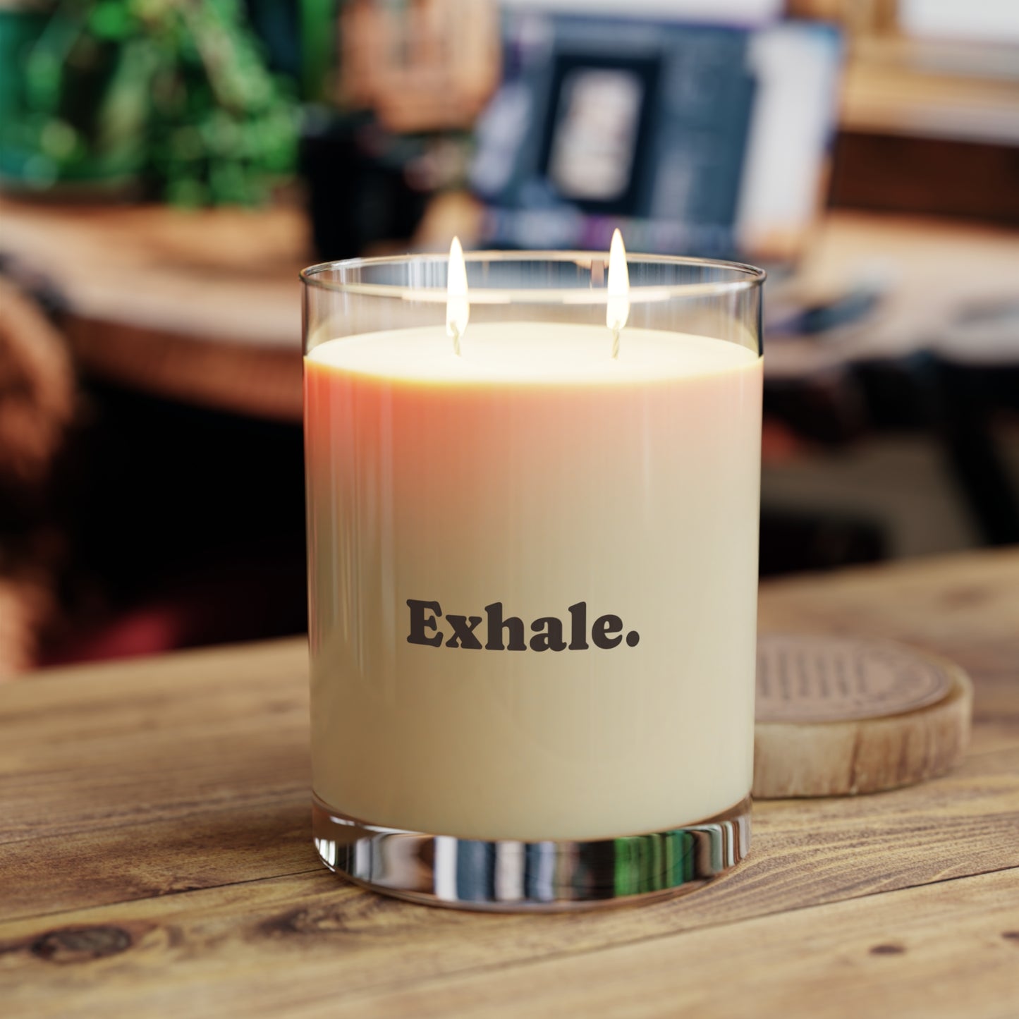 Soft Life Society Affirmation Candle in a glass jar labeled 'Exhale' on a wooden surface with a blurred background