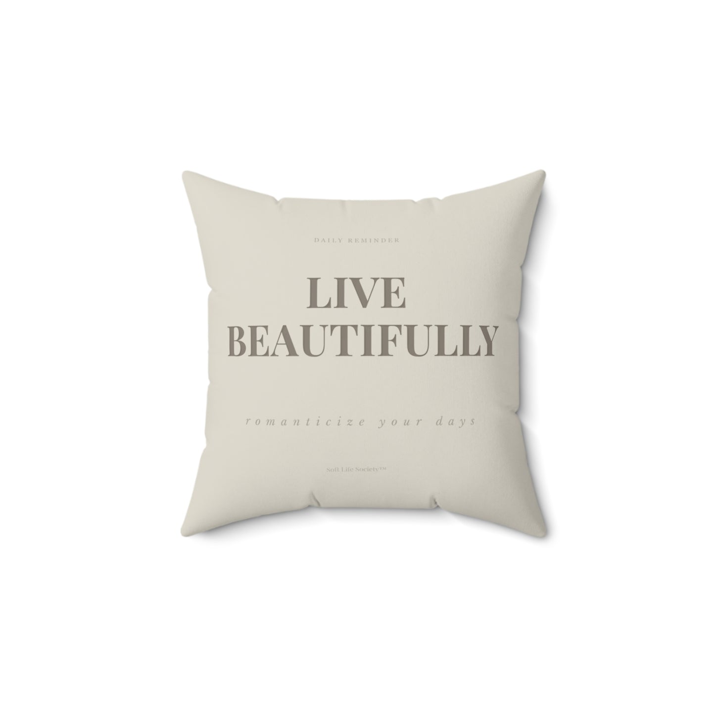 Beige pillow with 'Live Beautifully' text on a white background