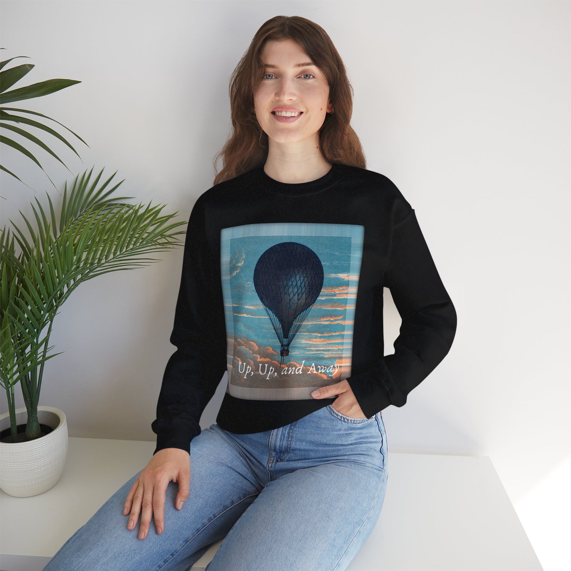 Lifestyle image of a woman wearing the "Up, Up, and Away" sweatshirt in black, seated indoors
