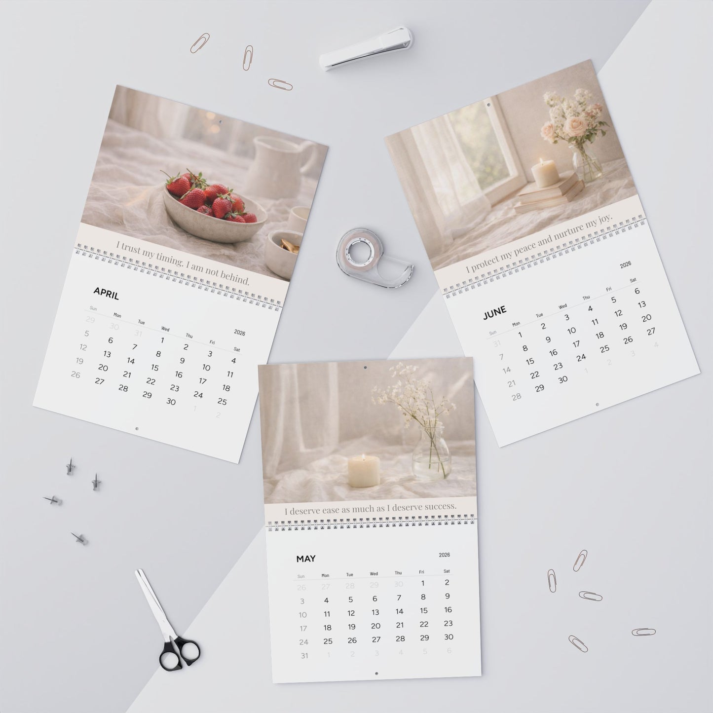 Three pages of a calendar showing April, May, and June on a light gray surface with office supplies.