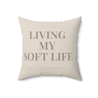 Beige pillow with text 'Living My Soft Life' on a white background