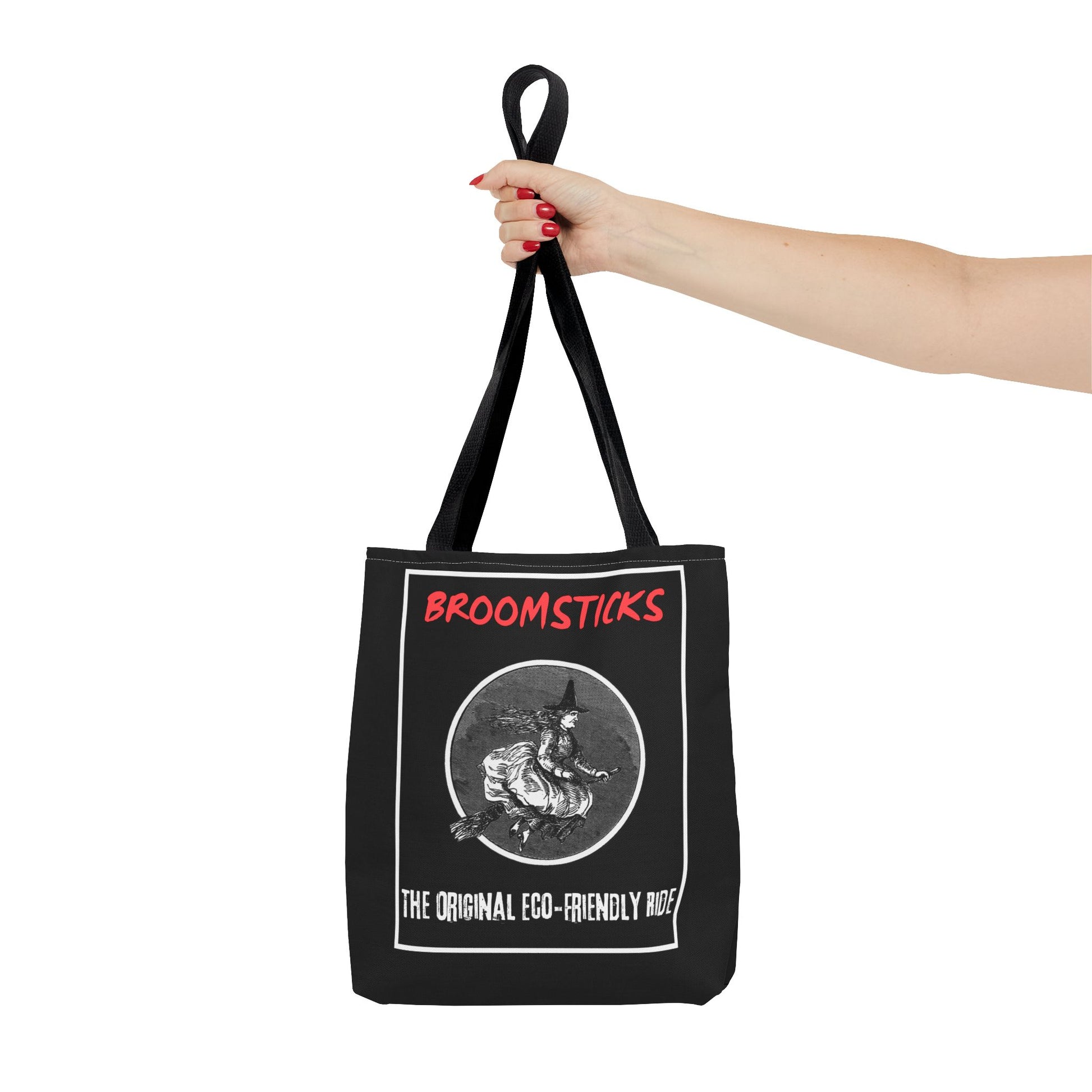 Close-up of the durable black handles, attached to a tote bag featuring a vintage witch design and humorous "eco-friendly ride" text.