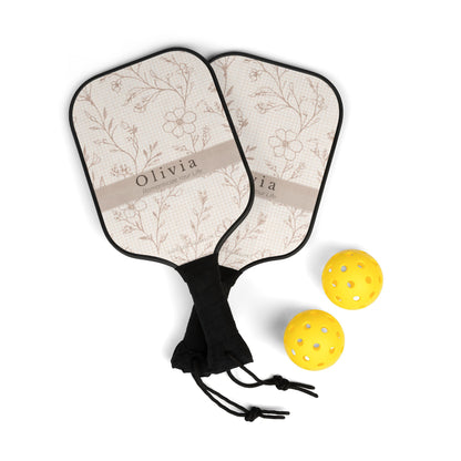 Two pickleball paddles with floral pattern and 'Olivia' branding, accompanied by two yellow pickleballs on a white background.