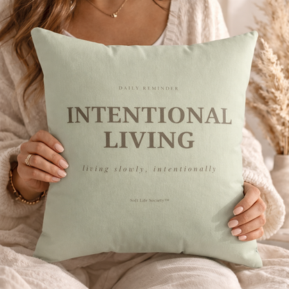 Person holding a pillow with 'Intentional Living' text