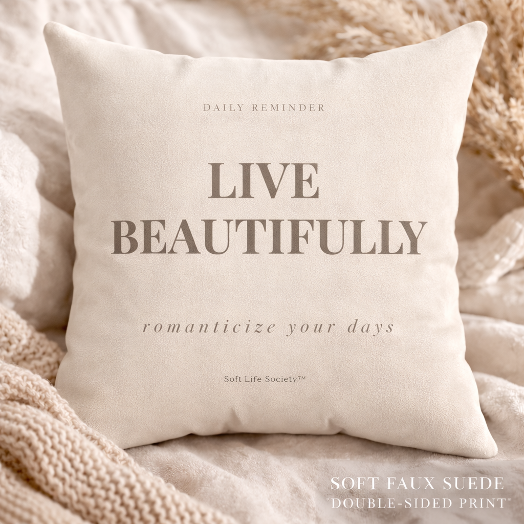 Beige pillow with 'Live Beautifully' text on a soft background