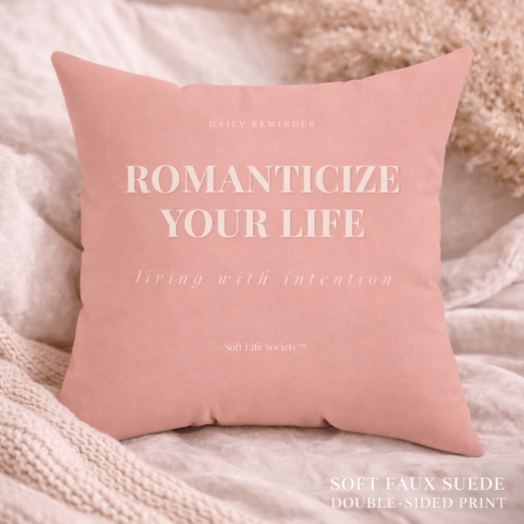 Pink pillow with text 'Romanticize Your Life' on a soft background