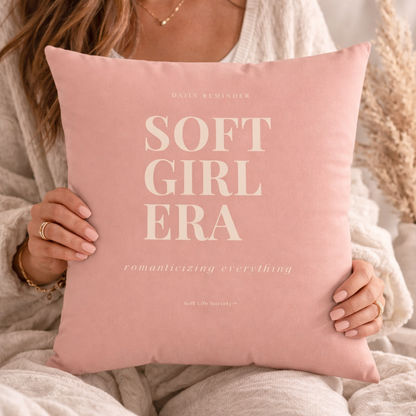 Person holding a pink pillow with 'SOFT GIRL ERA' text