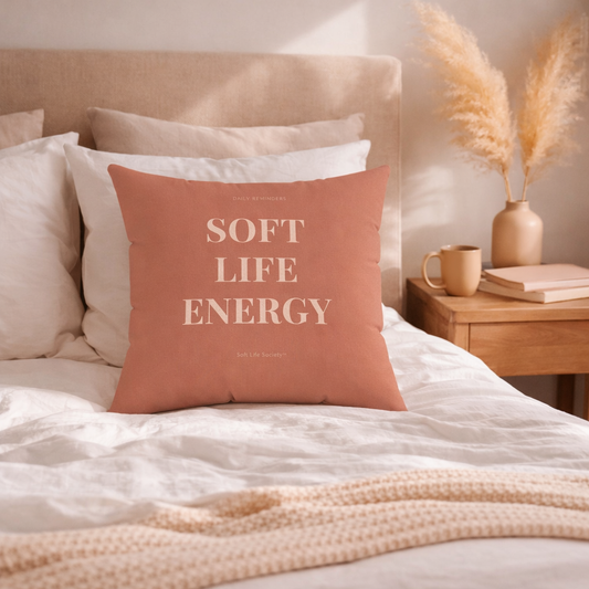 Decorative pillow with 'Soft Life Energy' text on a bed in a cozy bedroom setting.