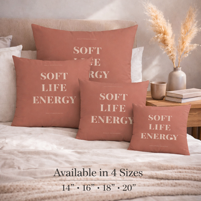 Decorative pillows with 'Soft Life Energy' text on a bed in a bedroom setting.