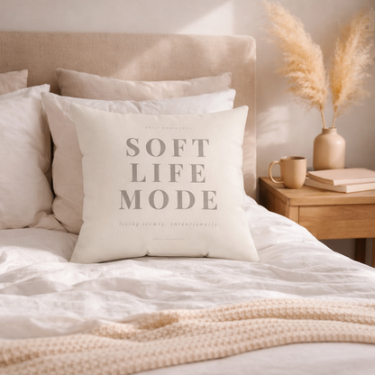 Decorative pillow with 'Soft Life Mode' text on a bed in a cozy bedroom setting.