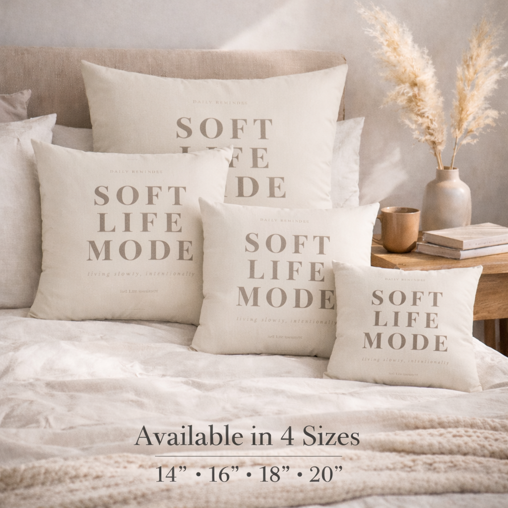 Decorative pillows with 'Soft Life Mode' text on a bed in a cozy bedroom setting.
