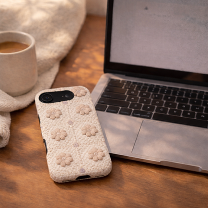 Phone with floral case next to a laptop on a wooden surface