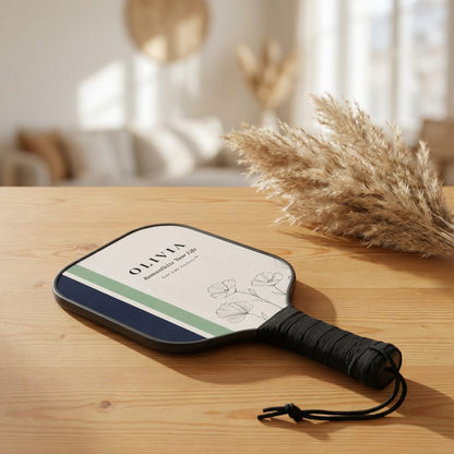 Paddle with 'Olivia' branding on a wooden surface with decorative elements