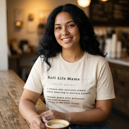 Woman wearing a 'Soft Life Mama' t-shirt in a cozy indoor setting