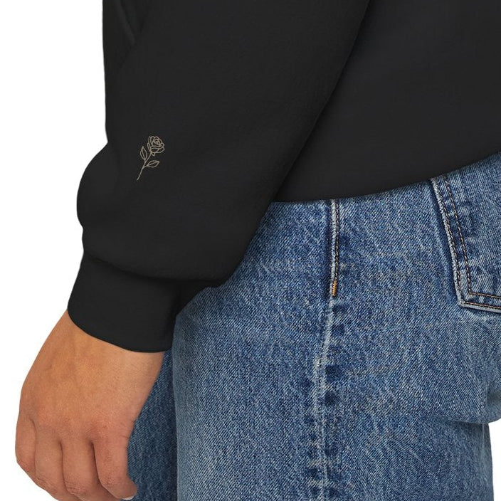 Close-up of subtle rose detail on the sleeve of a black Soft Life Society hoodie.