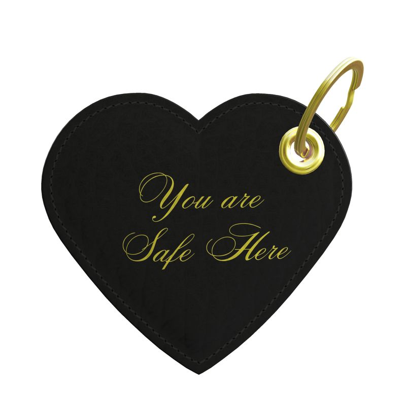 Black heart-shaped keychain with 'You are Safe Here' text and gold ring on a white background