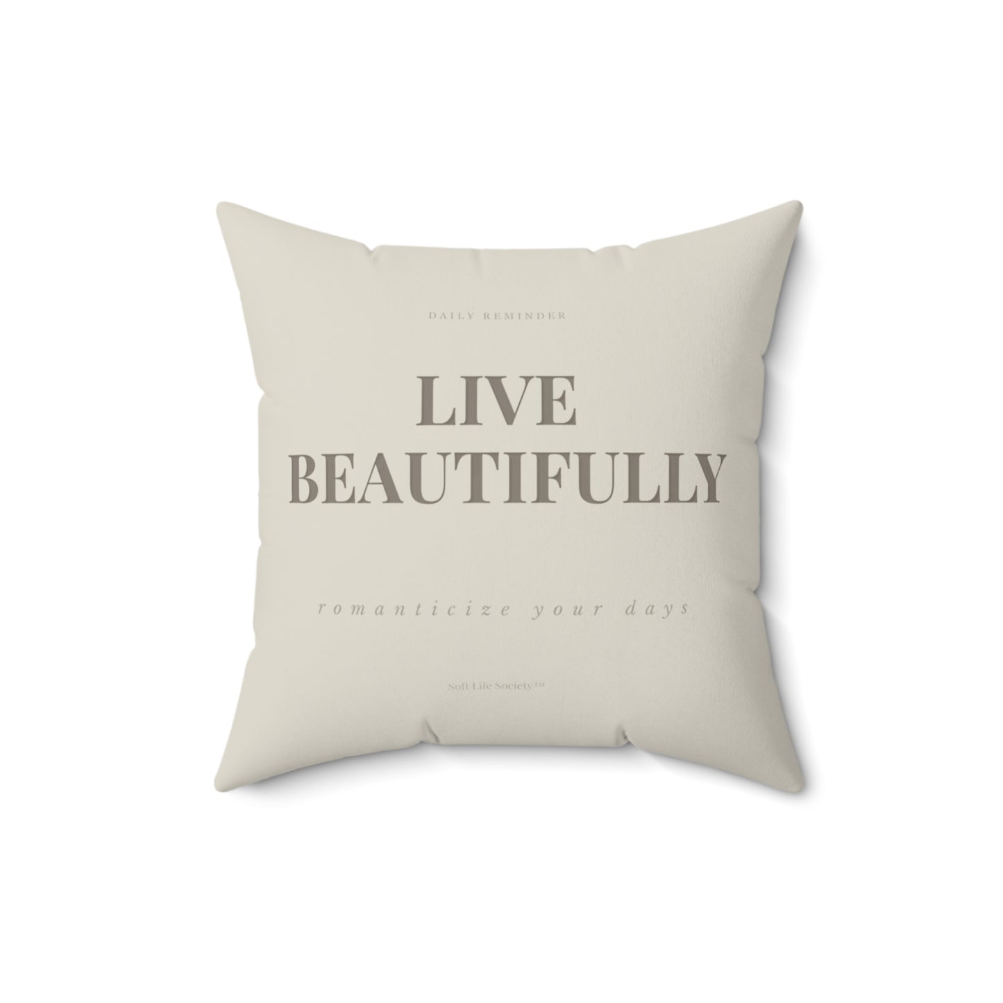 Beige pillow with 'Live Beautifully' text on a white background
