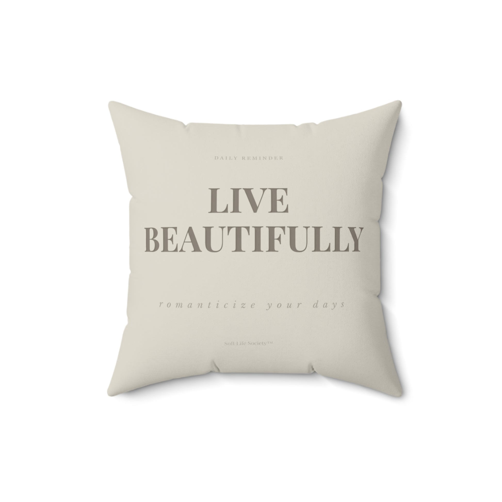 Beige pillow with 'Live Beautifully' text on a white background