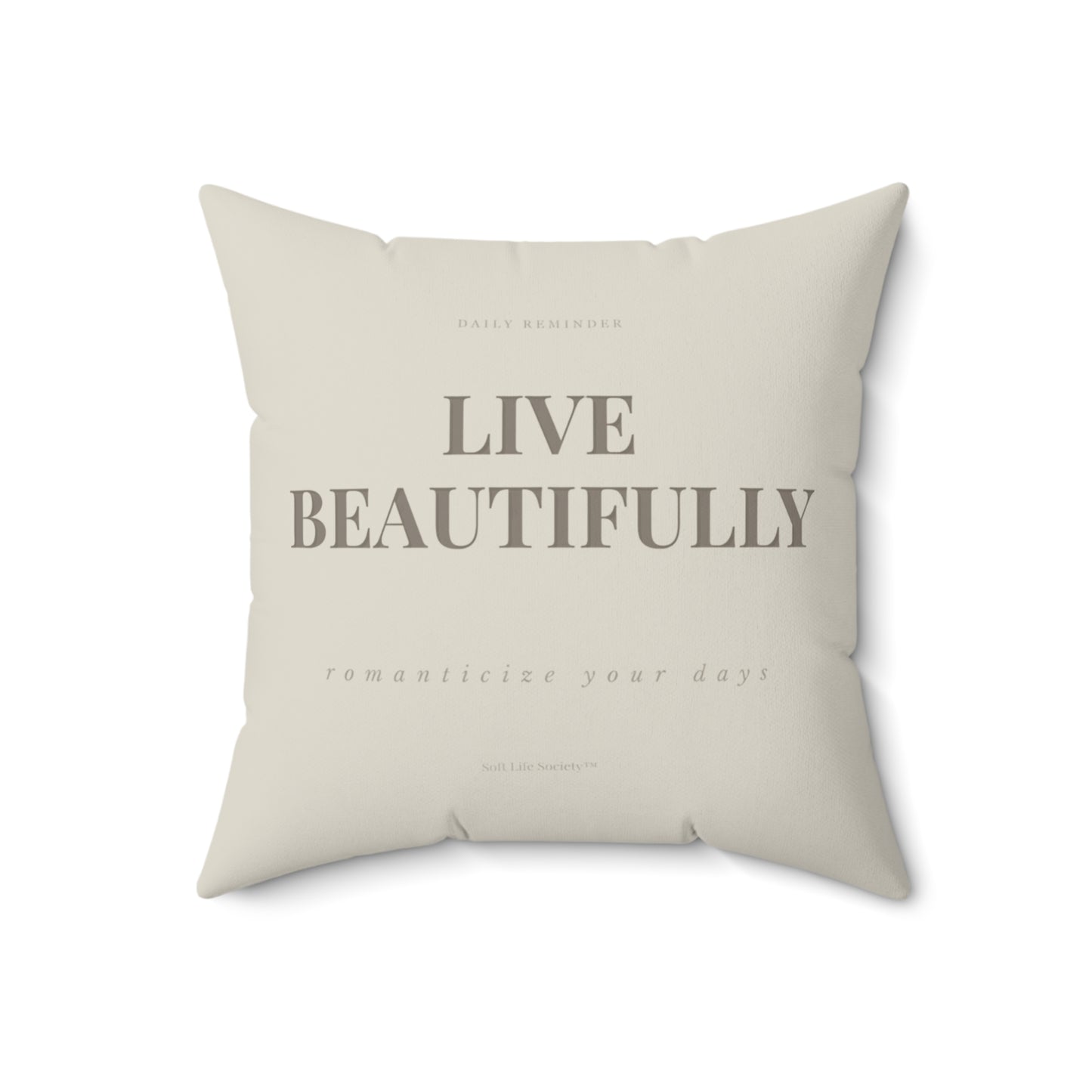 Beige pillow with 'Live Beautifully' text on a white background