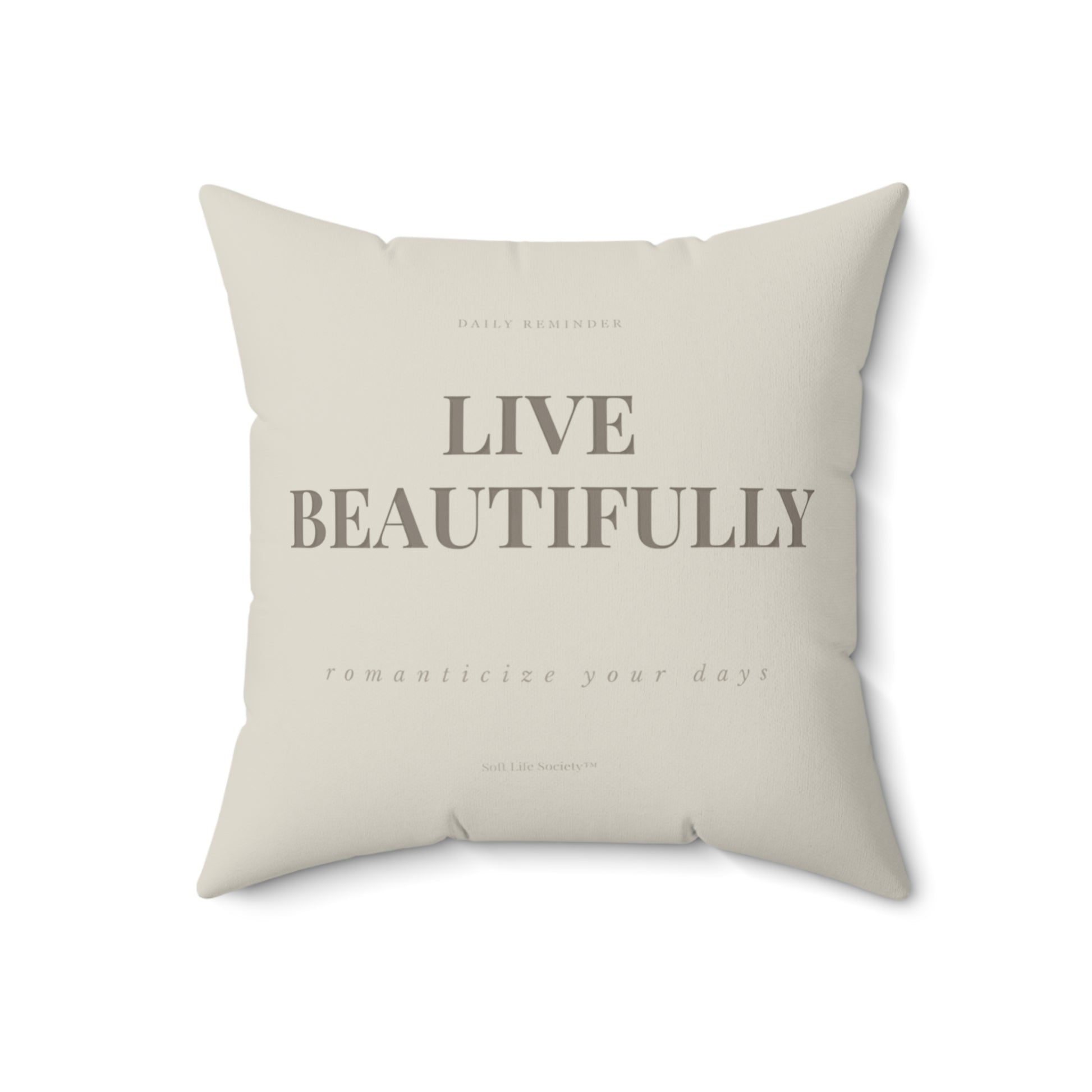 Beige pillow with 'Live Beautifully' text on a white background