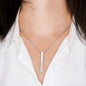 Silver necklace with a bar pendant on a person wearing a white shirt.