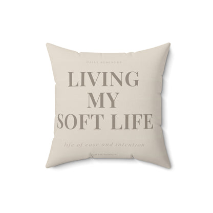 Beige pillow with text 'Living My Soft Life' on a white background