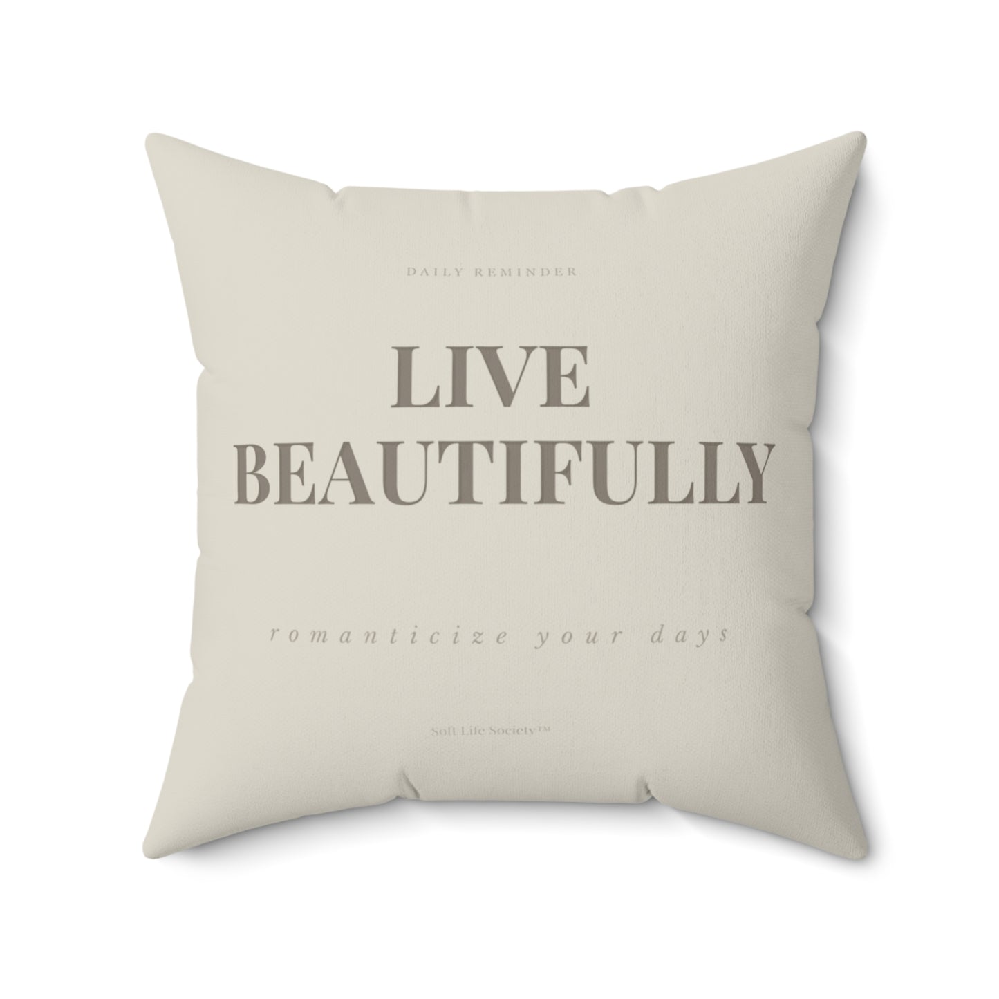 Beige pillow with 'Live Beautifully' text on a white background