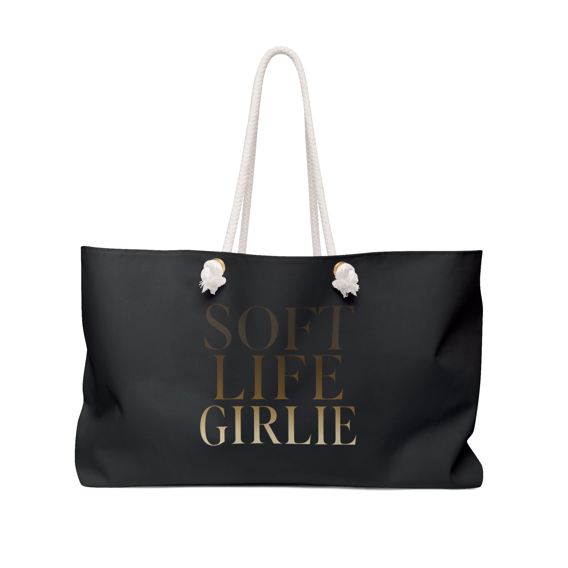 Black Soft Life Girlie weekender tote bag with gold-gradient text and white rope handles, displayed against a white background.