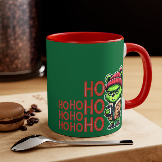 Green and red coffee mug featuring a playful Grinch-inspired teddy bear in a beanie and jacket, alongside bold 'HO HO OH' text, perfect for holiday drinks like coffee or hot cocoa.