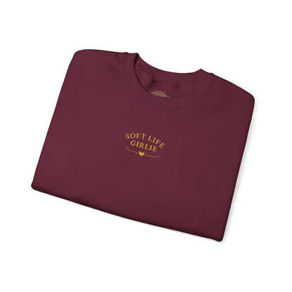 Folded maroon sweatshirt with 'SOFT LIFE GIRLIE' text on a white background
