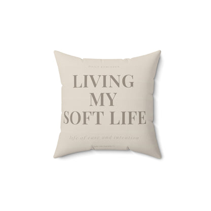 Beige pillow with text 'Living My Soft Life' on a white background