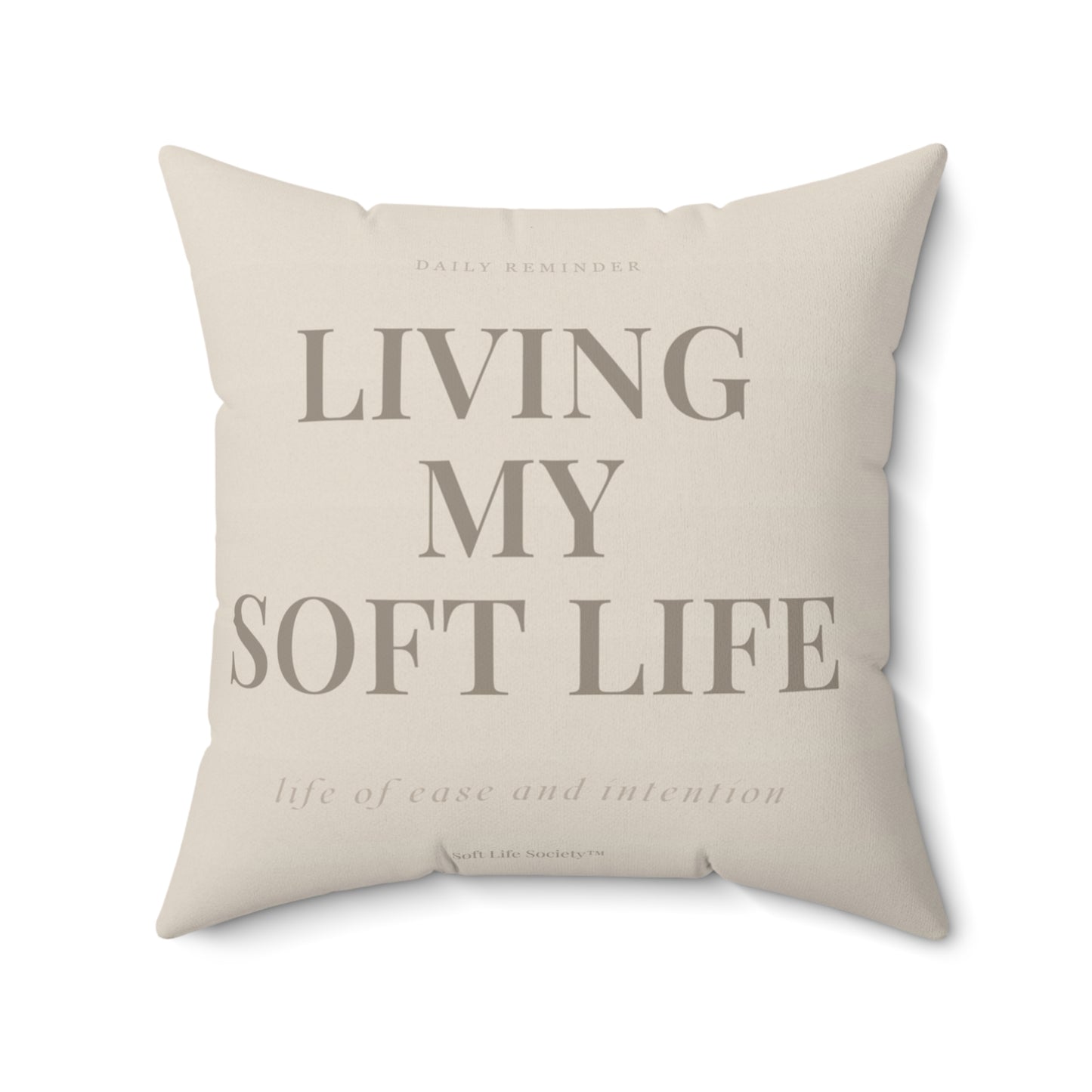Beige pillow with text 'Living my soft life' on a white background
